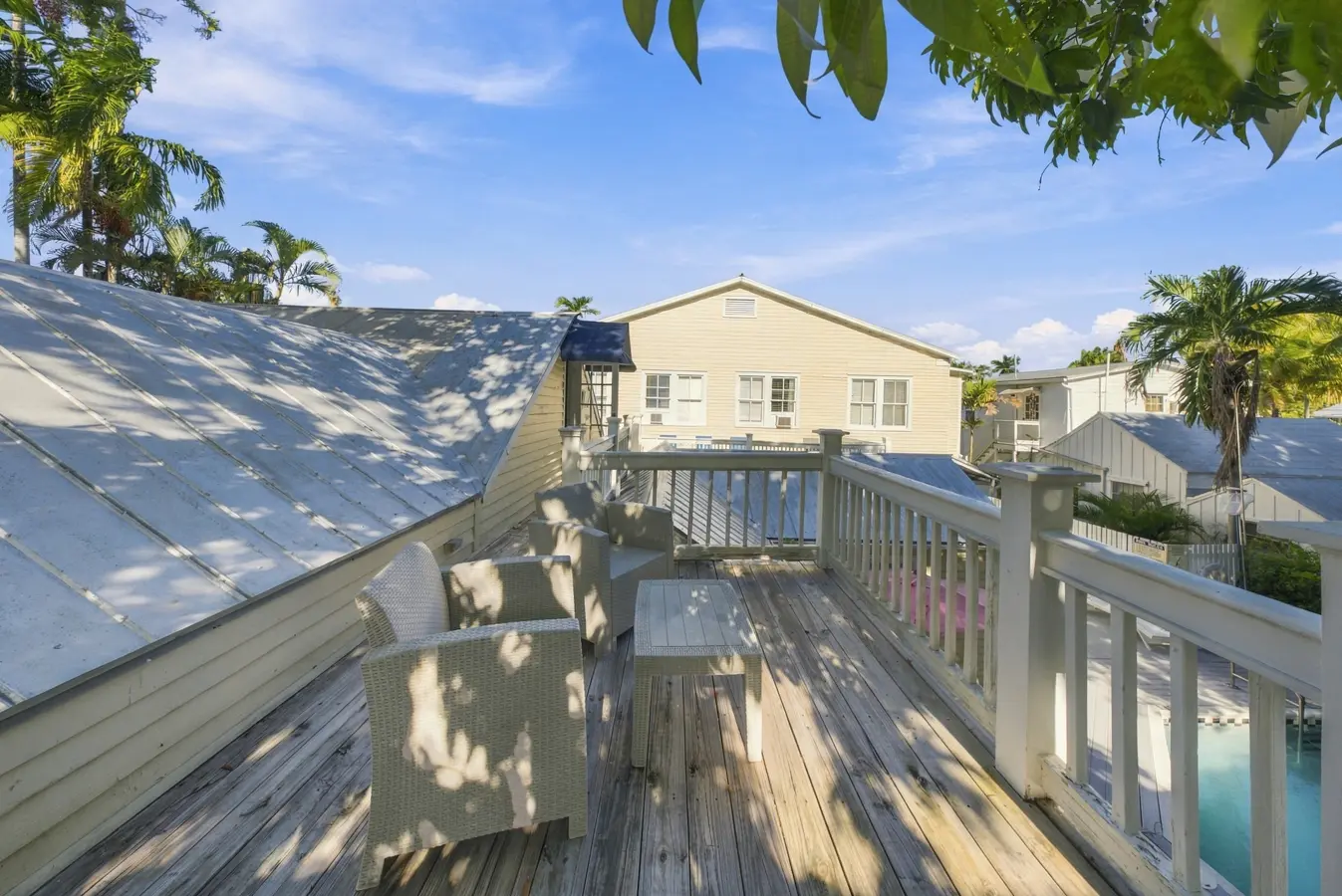 A deck with furniture overlooking a pool and buildings in the background.