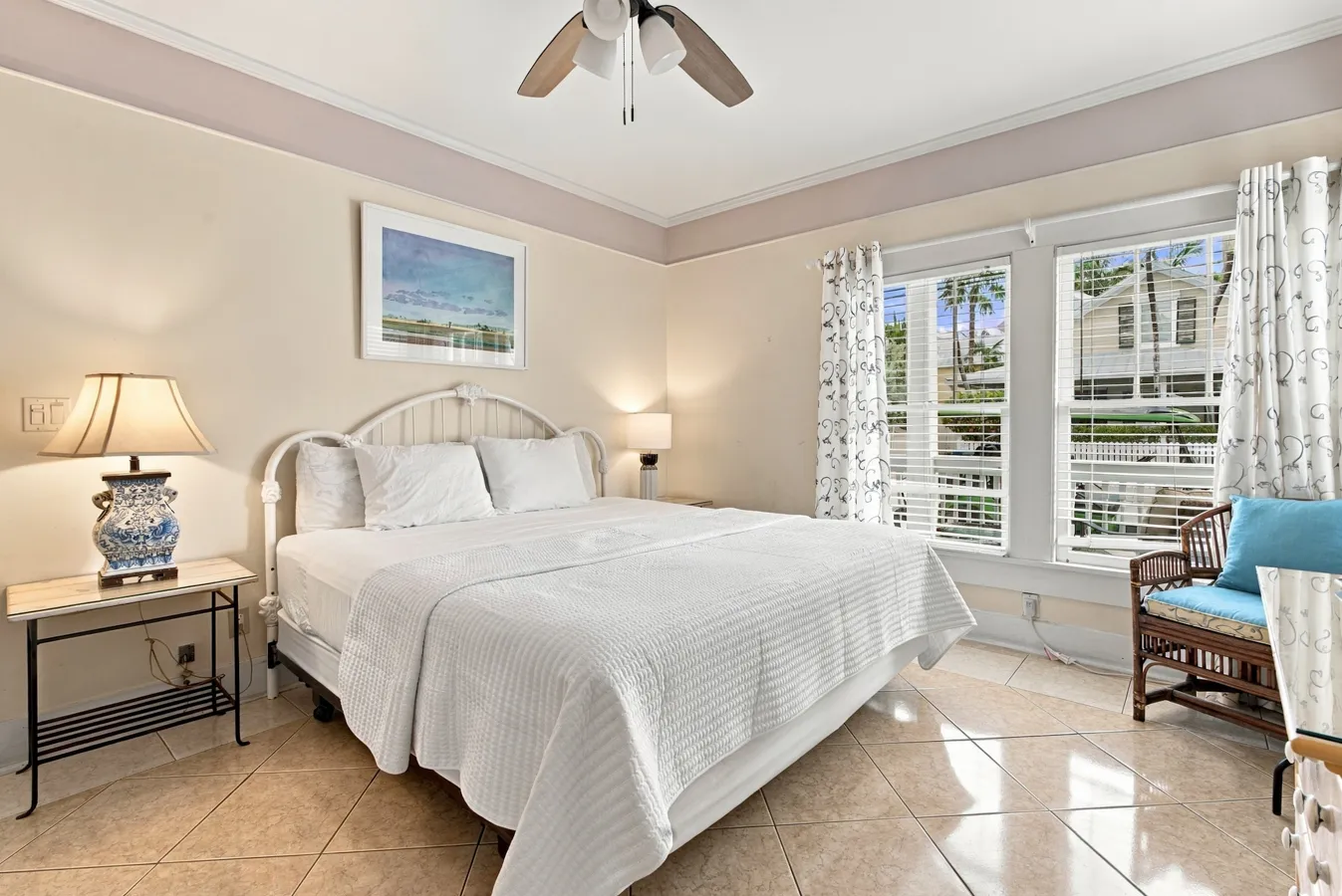 A hotel room with a large bed, nightstand, lamp, and window